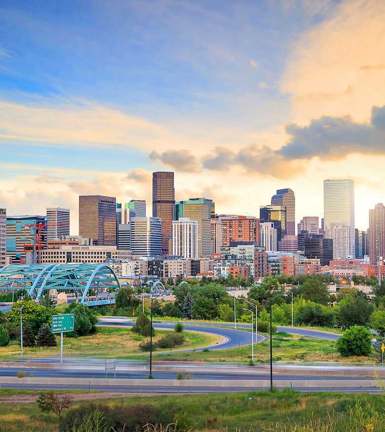 Sunrise over Denver's skyline with green parklands in the foreground, an attractive locale for personal injury lawyers.