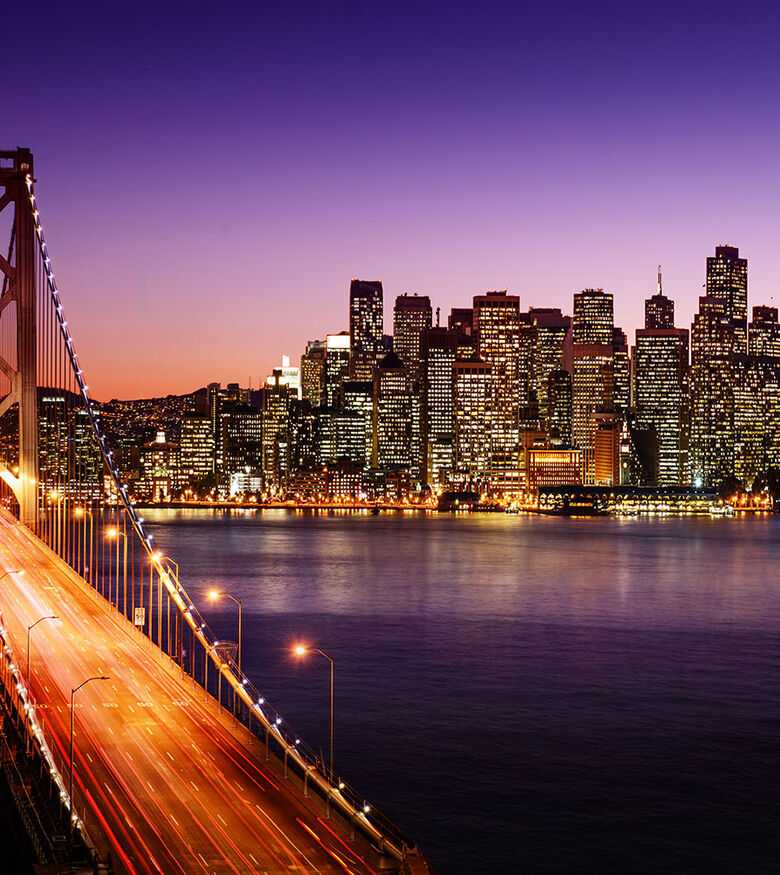 San Francisco skyline and Bay Bridge at twilight, glowing with lights, a hotspot for personal injury lawyers.