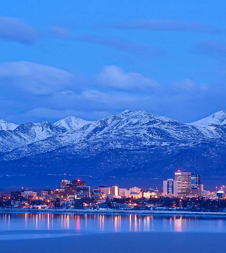 Anchorage city lights at dusk with snow-capped mountains in the background, a strategic location for personal injury lawyers.
