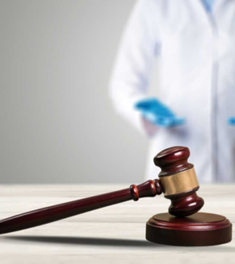 Gavel in focus with blurred healthcare professional in background