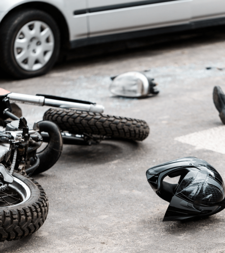 Motorcycle accident scene with helmet and overturned bike on pavement for motorcycle injury lawyer services