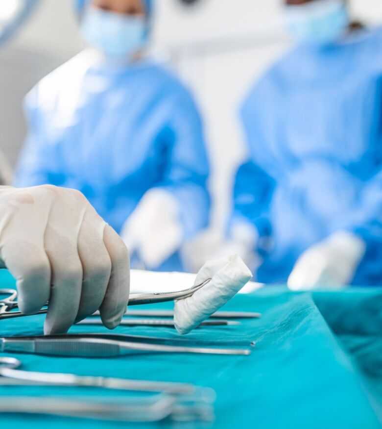 Surgical instruments laid out on a sterile table with a team of surgeons in the background