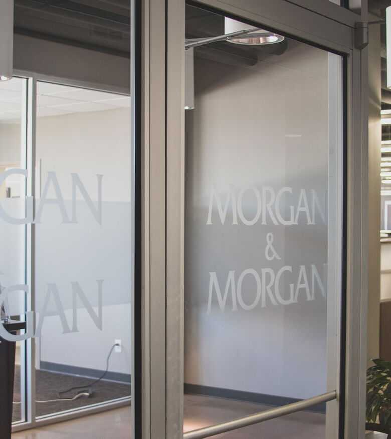 Glass entrance of a modern office building with 'Morgan & Morgan' logo in Bowling Green, suited for personal injury lawyers.