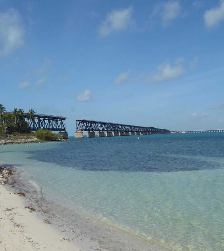 Tranquil beach view in Big Pine Key with clear blue waters and a bridge in the distance, ideal for Personal Injury Lawyers advertising.