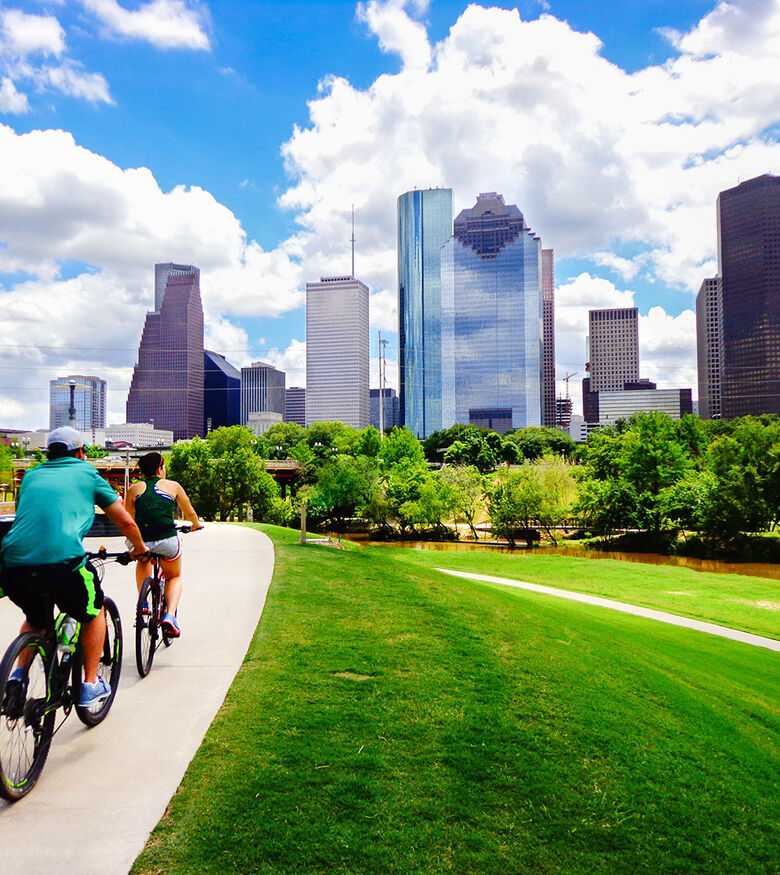 Cyclists on a park trail with Houston's vibrant cityscape in the background, illustrating a dynamic area for Personal Injury Lawyers.