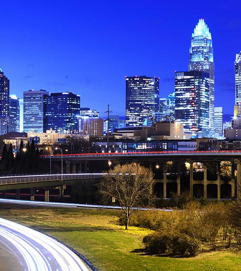 Bright, sunny view of Charlotte's modern skyline with green parks and bustling roads, a prime location for Personal Injury Lawyers.