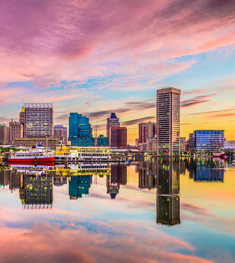 Baltimore skyline reflecting in the harbor at sunset, illustrating the secure presence of personal injury lawyers.
